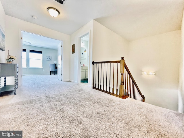 hall with carpet floors, an upstairs landing, and baseboards