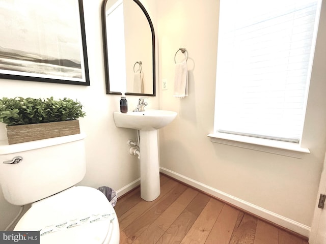 bathroom featuring toilet, wood-type flooring, and baseboards