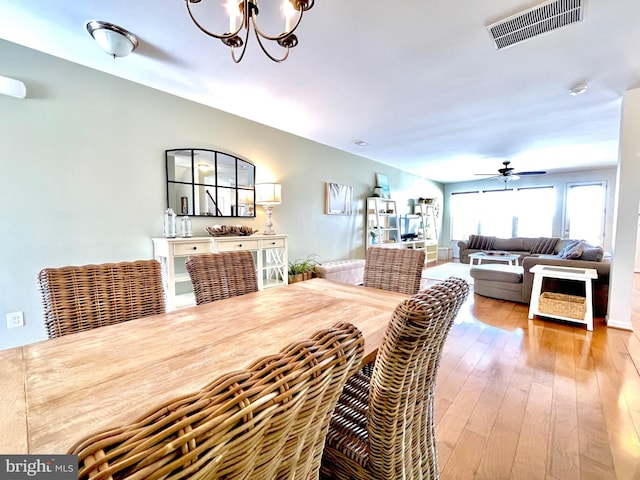 dining room featuring visible vents, hardwood / wood-style floors, and ceiling fan with notable chandelier