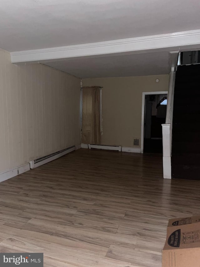 unfurnished room with a baseboard heating unit, visible vents, baseboard heating, and wood finished floors