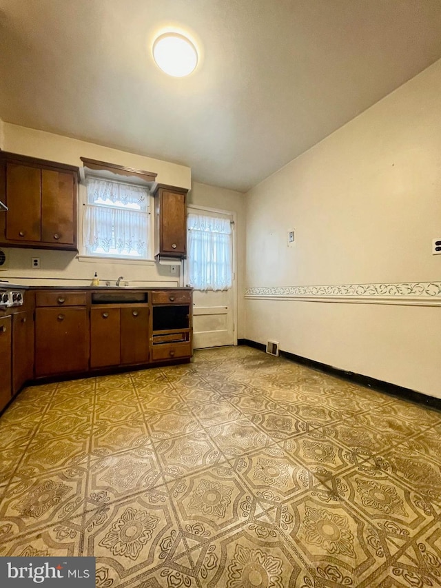 kitchen featuring light tile patterned floors, lofted ceiling, light countertops, visible vents, and baseboards