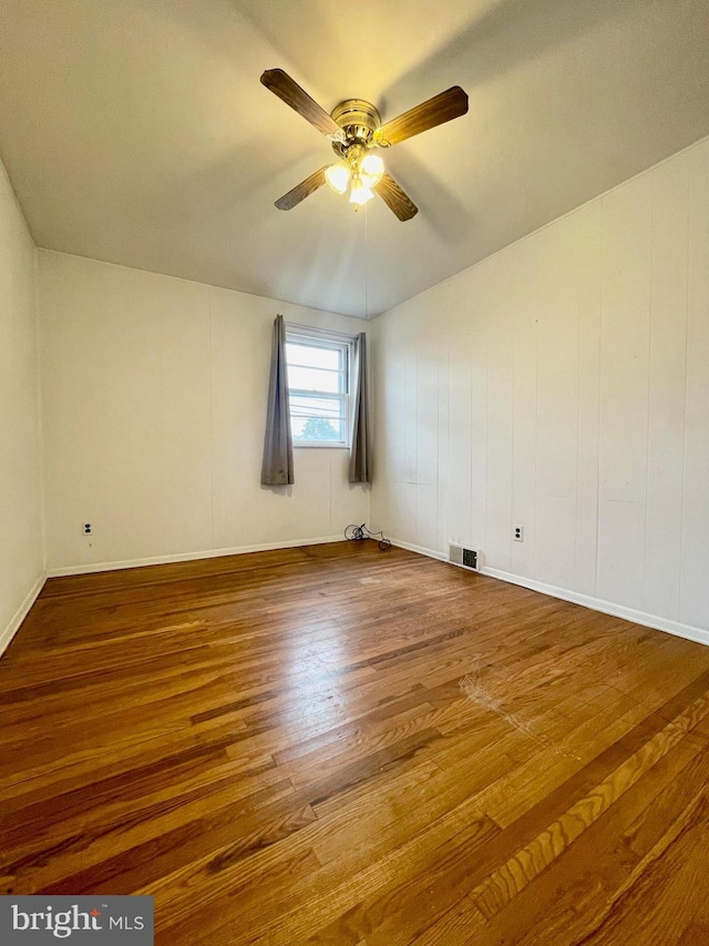 empty room with baseboards, ceiling fan, visible vents, and wood finished floors