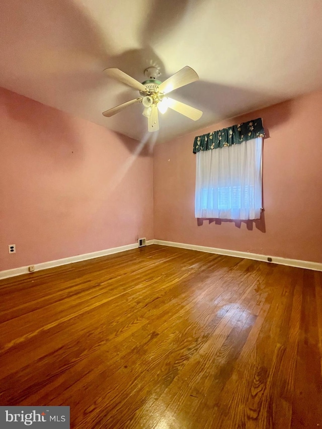 spare room with ceiling fan, wood finished floors, visible vents, and baseboards