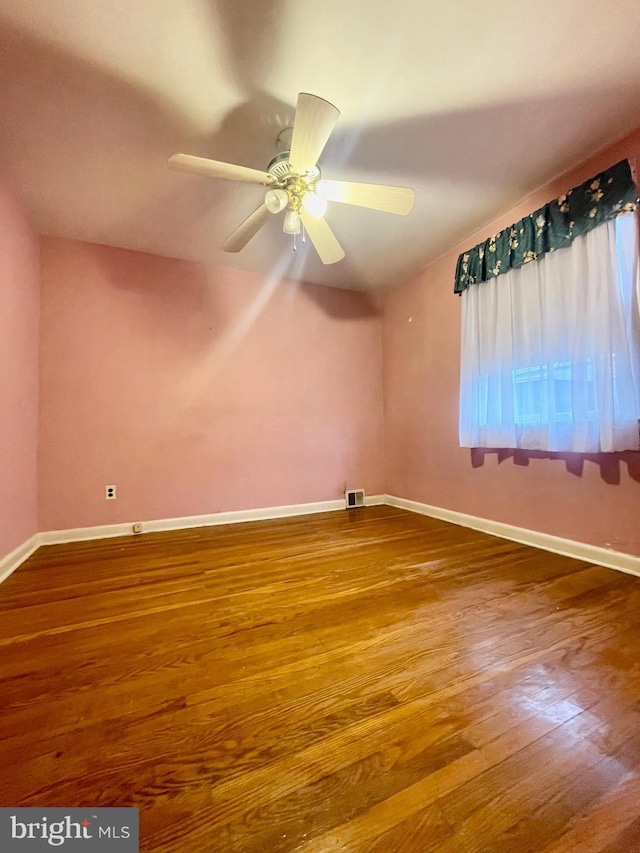 empty room with visible vents, ceiling fan, baseboards, and wood finished floors