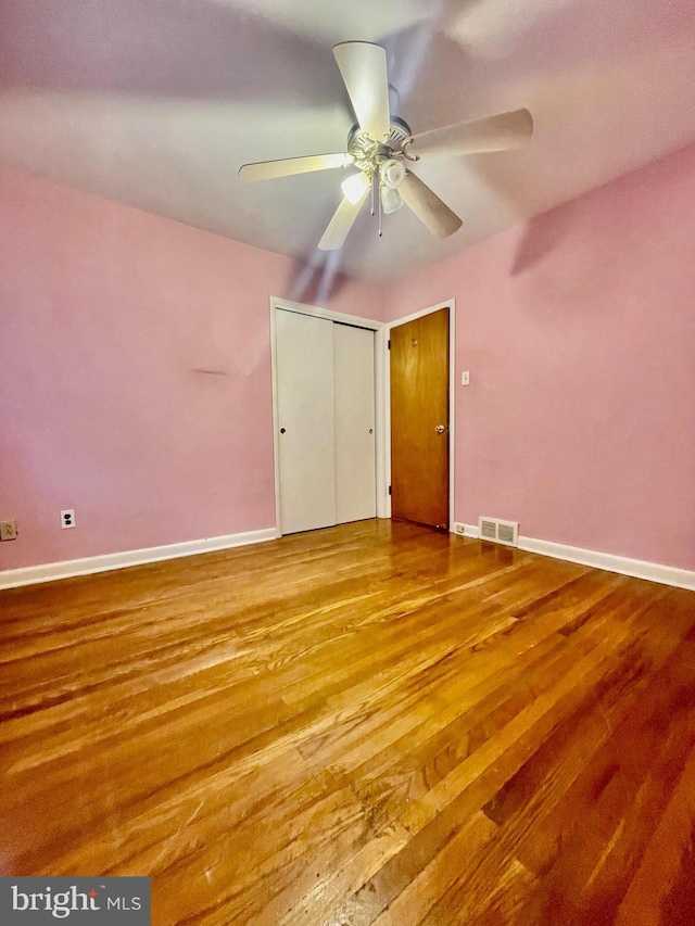 unfurnished bedroom featuring visible vents, baseboards, and wood finished floors