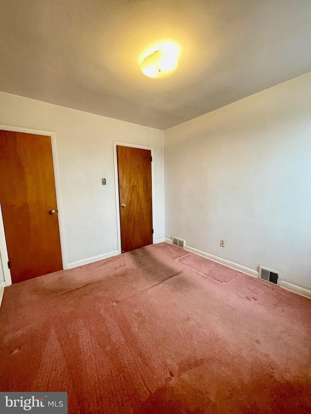 unfurnished room with carpet floors, visible vents, and baseboards