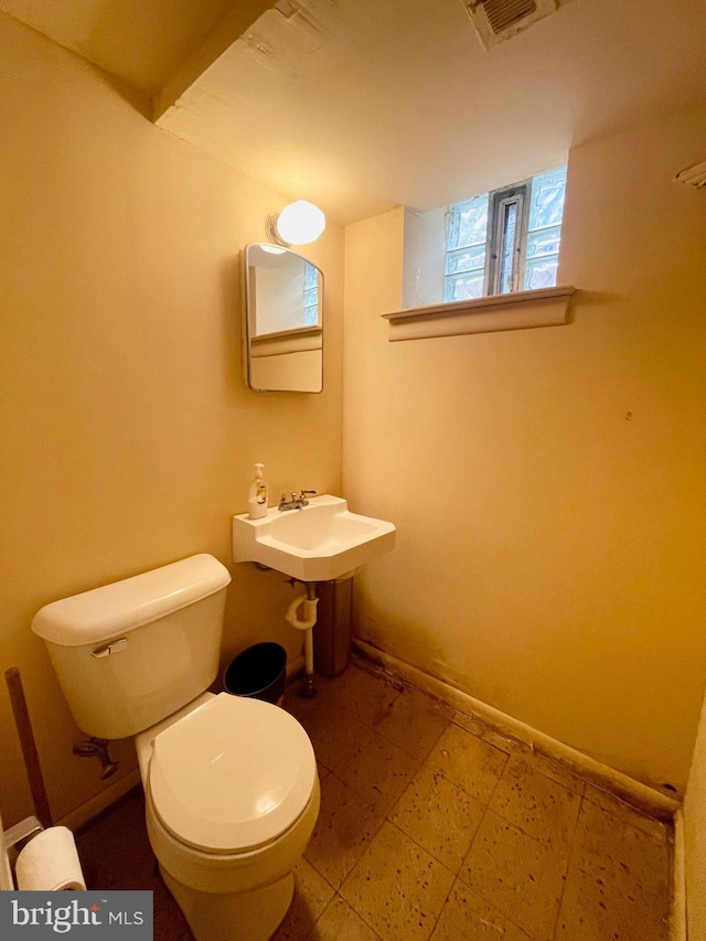 half bathroom featuring visible vents, a sink, toilet, and baseboards