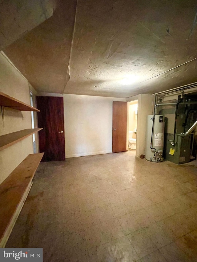 finished basement with gas water heater, heating unit, and tile patterned floors