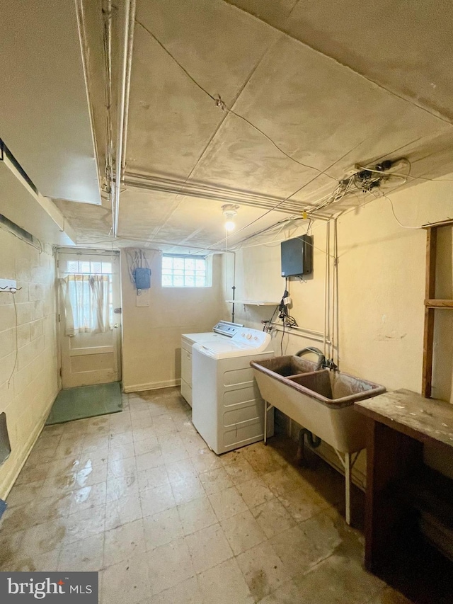 washroom with concrete block wall, light floors, separate washer and dryer, and a sink