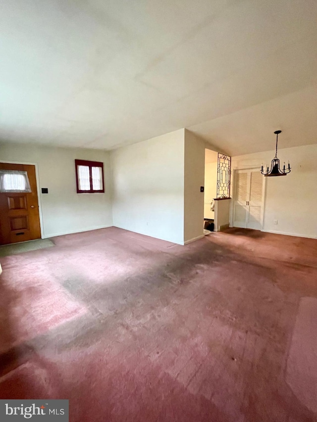 unfurnished living room with carpet floors and an inviting chandelier