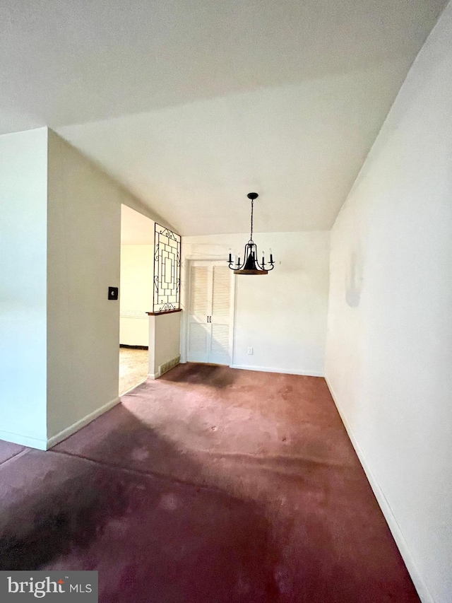 unfurnished dining area with carpet floors, an inviting chandelier, and baseboards