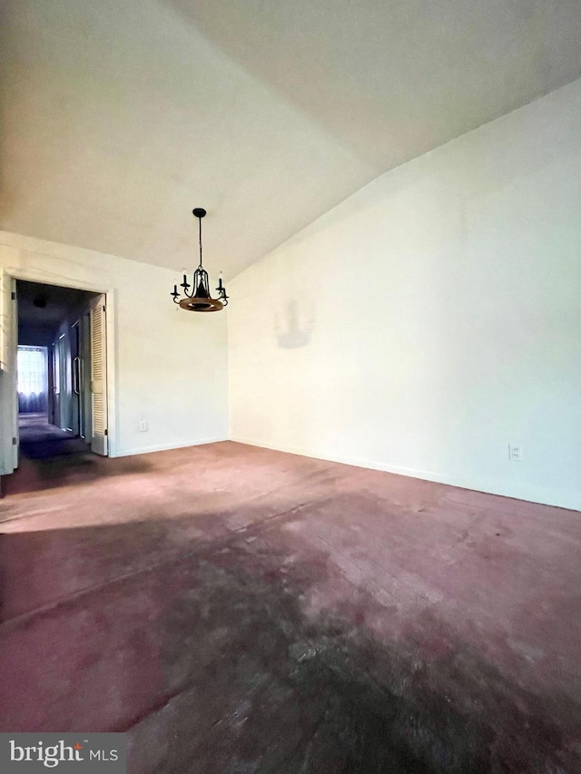 unfurnished dining area with vaulted ceiling, concrete floors, and an inviting chandelier