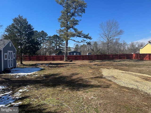view of yard featuring fence, an outdoor structure, and a storage unit