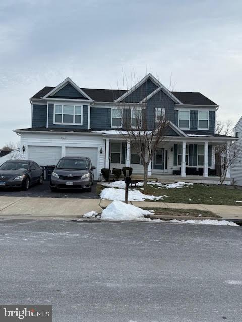 view of front of home featuring a garage, covered porch, and driveway