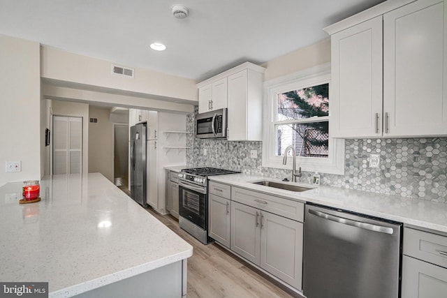 kitchen with open shelves, visible vents, decorative backsplash, appliances with stainless steel finishes, and a sink