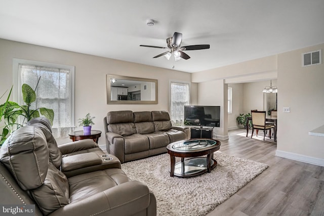 living area with baseboards, visible vents, wood finished floors, and ceiling fan with notable chandelier