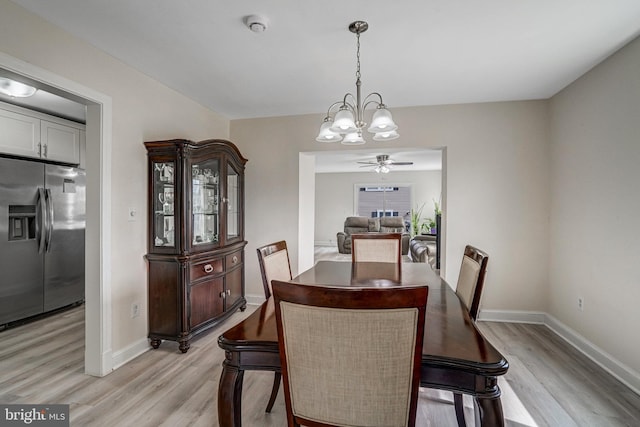 dining space featuring baseboards, ceiling fan with notable chandelier, and light wood-style floors