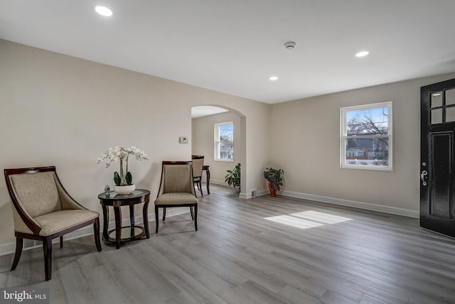 living area featuring arched walkways, recessed lighting, baseboards, and wood finished floors