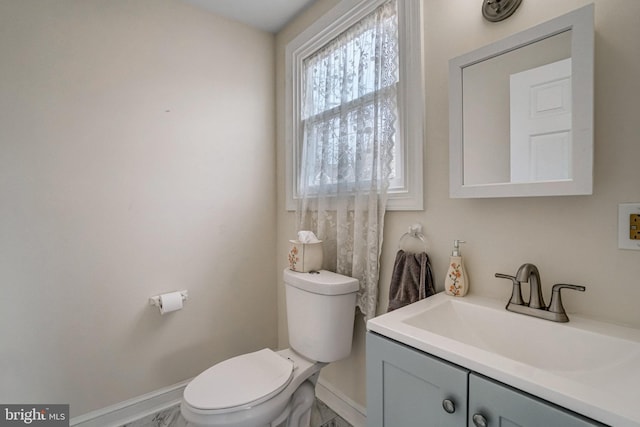 half bathroom featuring vanity, toilet, and baseboards