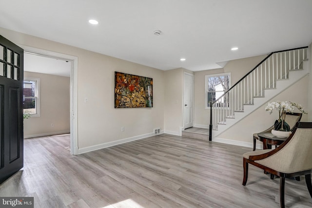 foyer entrance featuring stairs, light wood-type flooring, and baseboards