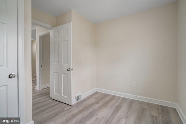 unfurnished room with light wood-style floors, visible vents, and baseboards