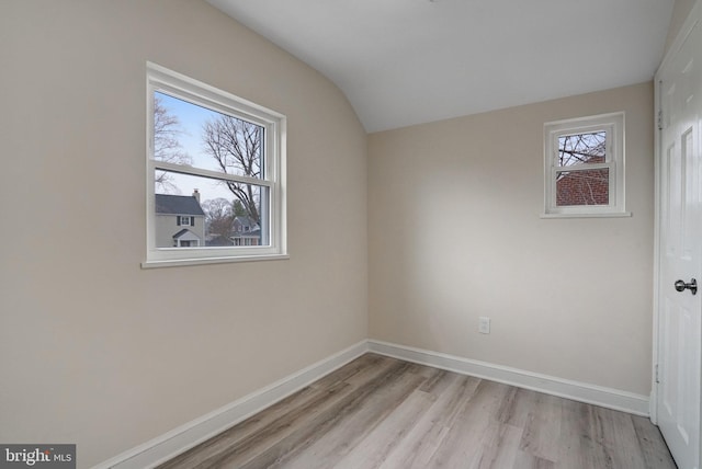 unfurnished bedroom featuring lofted ceiling, light wood-style flooring, and baseboards