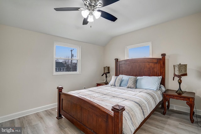 bedroom with light wood-type flooring, vaulted ceiling, baseboards, and ceiling fan