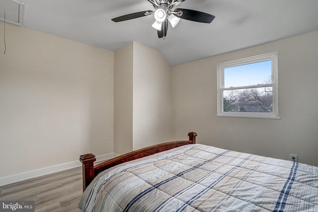 bedroom with ceiling fan, wood finished floors, baseboards, vaulted ceiling, and attic access