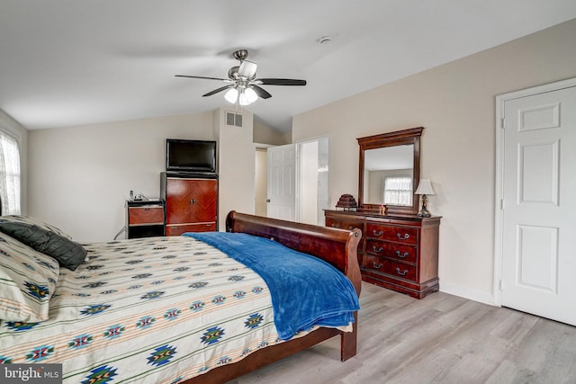 bedroom featuring lofted ceiling, visible vents, baseboards, a ceiling fan, and light wood-type flooring