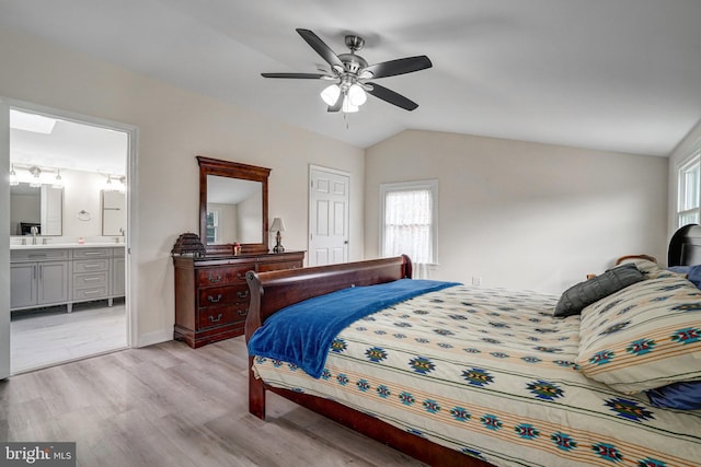 bedroom featuring light wood finished floors, ceiling fan, vaulted ceiling, and connected bathroom