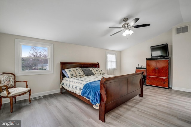 bedroom with vaulted ceiling, wood finished floors, visible vents, and baseboards