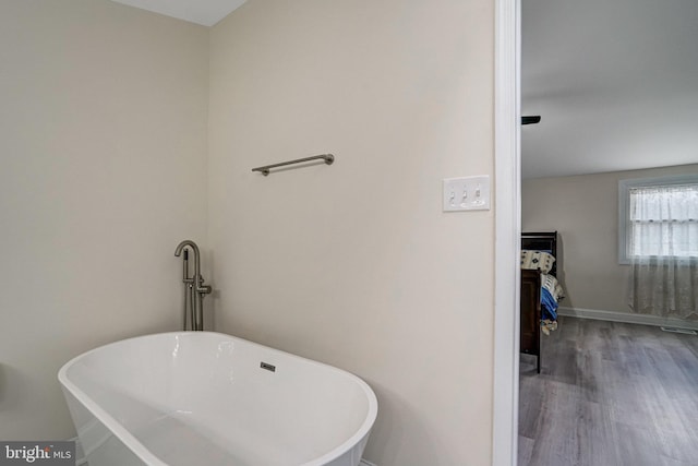 full bath featuring a soaking tub, wood finished floors, and baseboards