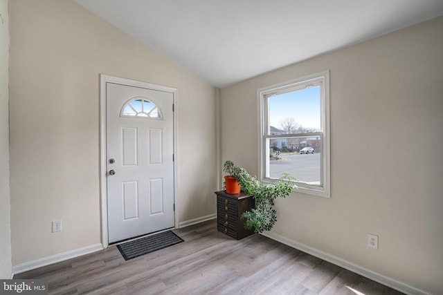 entrance foyer featuring lofted ceiling, light wood-style flooring, and baseboards