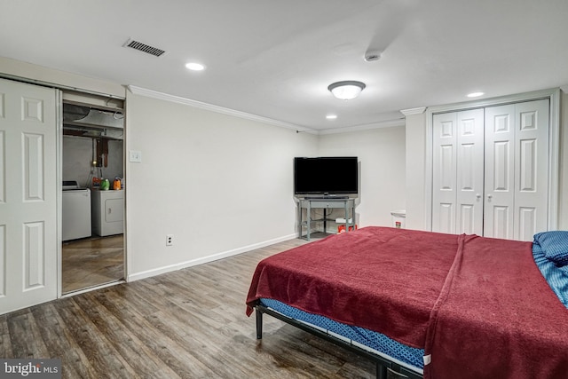 bedroom with visible vents, ornamental molding, wood finished floors, and independent washer and dryer