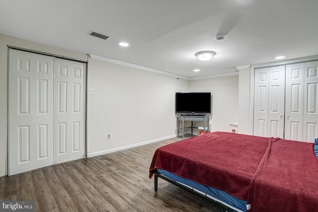 bedroom with baseboards, visible vents, wood finished floors, crown molding, and recessed lighting