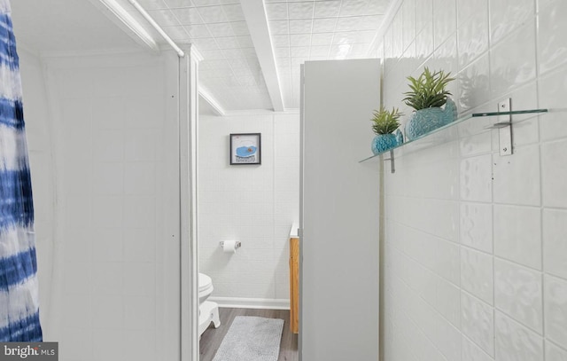 bathroom with tile walls, toilet, and wood finished floors