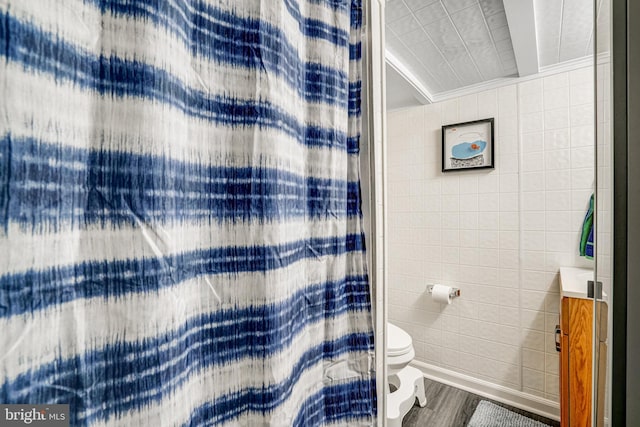 bathroom featuring a shower with curtain, wood finished floors, toilet, and tile walls