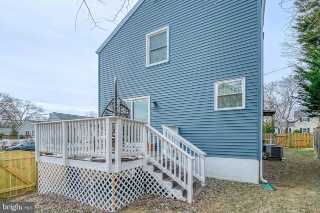 rear view of house with central AC unit, fence, and a deck