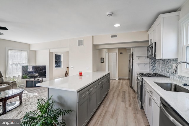 kitchen with visible vents, appliances with stainless steel finishes, open floor plan, light countertops, and a sink