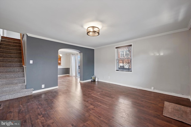 spare room featuring stairs, arched walkways, wood finished floors, and ornamental molding