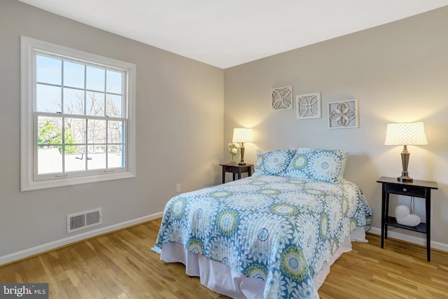 bedroom featuring wood finished floors, visible vents, and baseboards