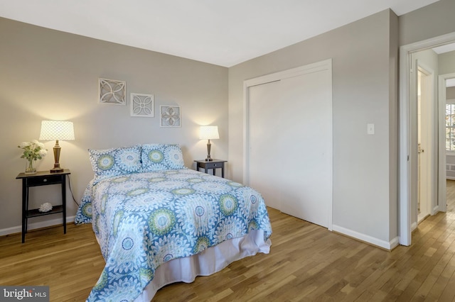 bedroom with a closet, wood finished floors, and baseboards