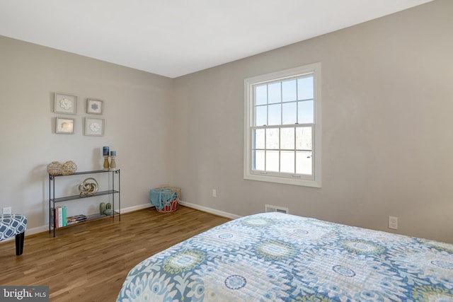 bedroom featuring baseboards, visible vents, and wood finished floors