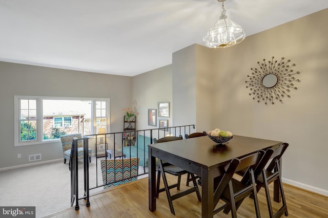 dining area featuring light wood finished floors, visible vents, and baseboards