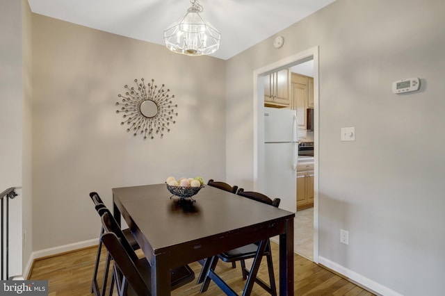 dining area with light wood-style floors, a chandelier, and baseboards