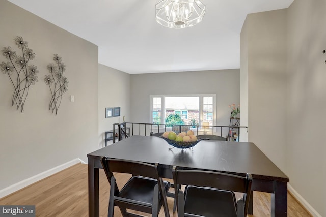 dining space featuring light wood-style flooring, baseboards, and a notable chandelier