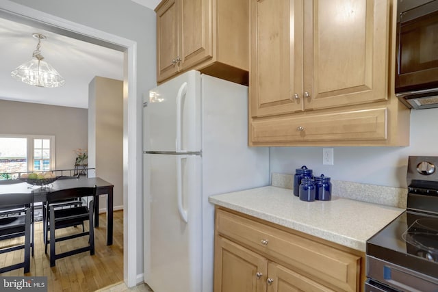 kitchen featuring electric range oven, freestanding refrigerator, light countertops, light brown cabinetry, and black microwave