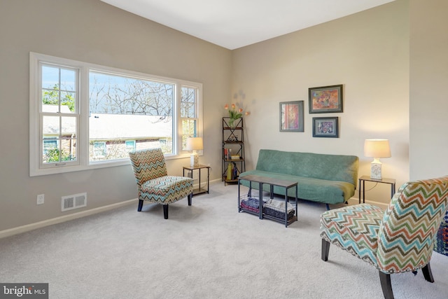 sitting room with carpet floors, a wealth of natural light, visible vents, and baseboards