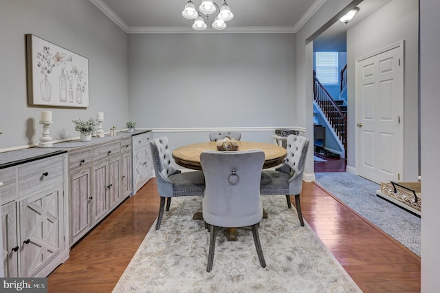 dining room with dark wood-type flooring, crown molding, stairway, and an inviting chandelier