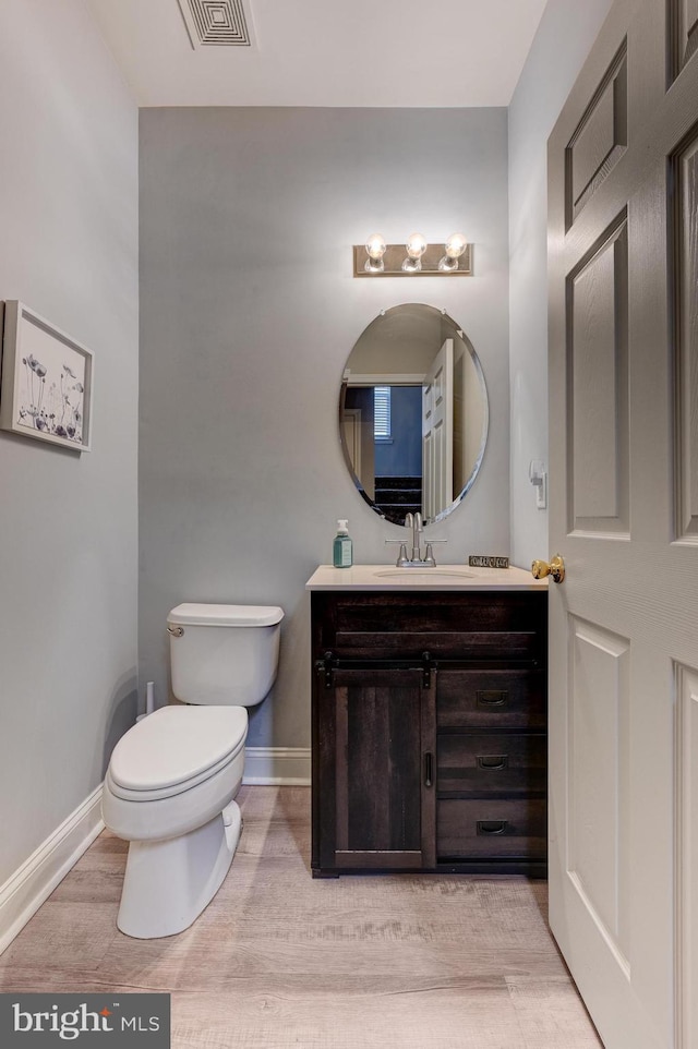 bathroom featuring toilet, baseboards, visible vents, and wood finished floors